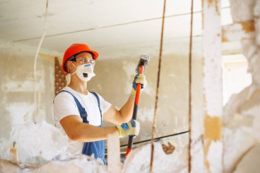 Kasklı bir tamirci ve aletli bir kazan giysisi. Daire tamiri ve yenileme konsepti. İnşaat, çalışma ekipmanları ve insan konsepti