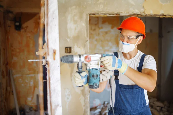 Repairer in hardhat  and boiler suit with tools. Apartment repair and renovation concept. Building, working equipment and people concept