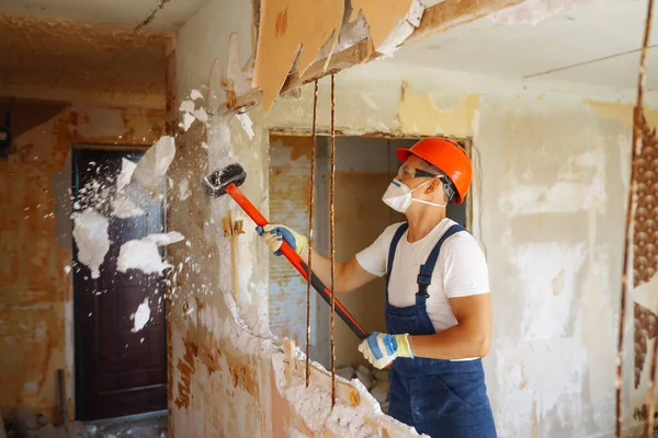 Kasklı bir tamirci ve aletli bir kazan giysisi. Daire tamiri ve yenileme konsepti. İnşaat, çalışma ekipmanları ve insan konsepti