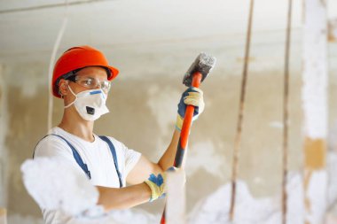 Kasklı bir tamirci ve aletli bir kazan giysisi. Daire tamiri ve yenileme konsepti. İnşaat, çalışma ekipmanları ve insan konsepti