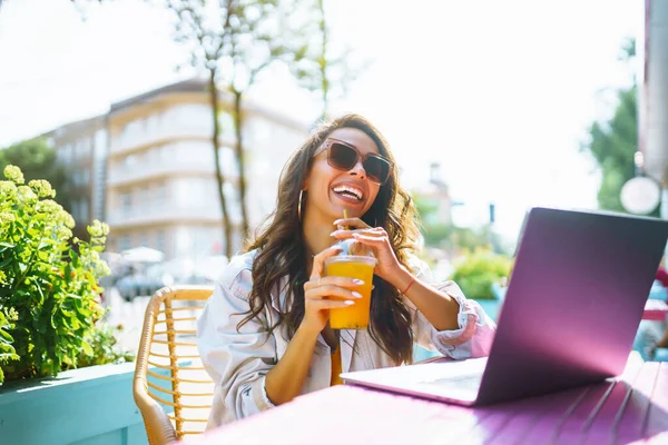 Portrait of happy young  woman with a laptop at cafe. Freelancer working on a laptop.  Business, online, education concept.