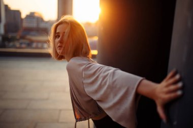 Çatıda poz veren genç bir kadın, çatıdan şehrin muhteşem manzarası. İnsanlar, yaşam tarzı, rahatlama konsepti. Moda, tarz kavramı.