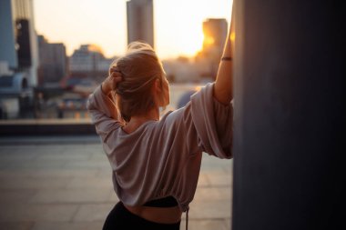 Çatıda poz veren genç bir kadın, çatıdan şehrin muhteşem manzarası. İnsanlar, yaşam tarzı, rahatlama konsepti. Moda, tarz kavramı.