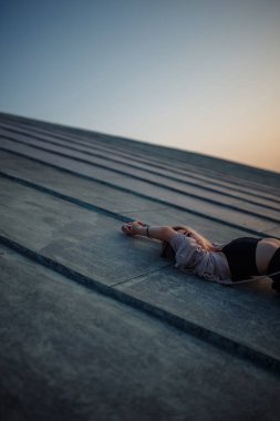 Gün batımında çatıda poz veren genç bir kadın, Özgürlük Şehri atmosferi. İnsanlar, yaşam tarzı, rahatlama konsepti.