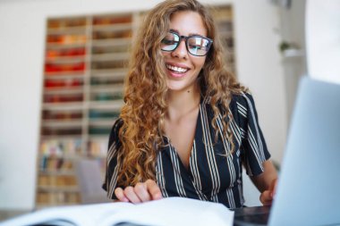 Genç ve güzel bir kız öğrenci, üniversite kütüphanesinde çalışıyor. Eğitim kavramı, çevrimiçi öğrenme, teknoloji.