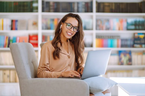 Jonge Vrouw Met Een Draadloze Koptelefoon Die Belt Een Laptop — Stockfoto