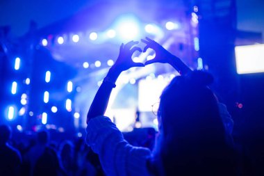 Kalp şeklinde eller konserde, sanatçıya ve festivale bayılıyor. Konserden keyif alan insanların ışık ve siluetiyle müzik konseri.