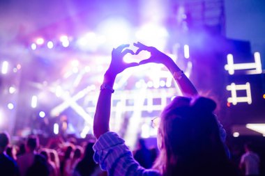 Kalp şeklinde eller konserde, sanatçıya ve festivale bayılıyor. Konserden keyif alan insanların ışık ve siluetiyle müzik konseri.
