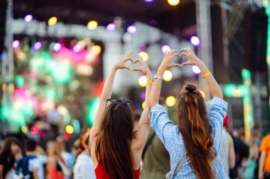 Heart shaped hands at concert, loving the artist and the festival. Music concert with lights and silhouette of people enjoying the concert. clipart