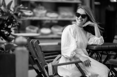 Genç kadın rahat bir kafede takılıyor, etrafa bakıyor, mutlu duygular içinde. Gezgin kadın..