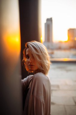 Güzel bir kadın çatıda duruyor ve gün batımında mutlu oluyor. Yaz havası. Özgürlük için. İnsanlar, yaşam tarzı, rahatlama konsepti. Moda, tarz kavramı.