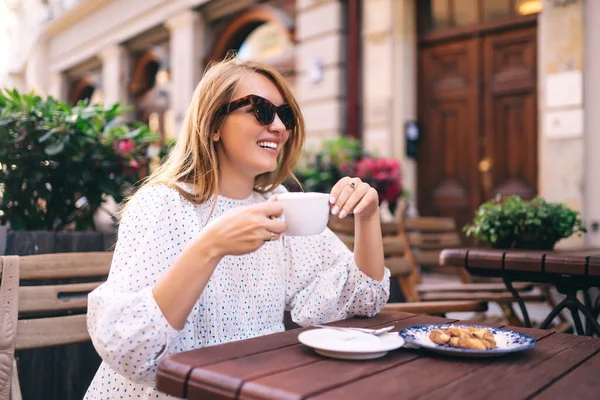 Güzel bir kadın, şehir caddesinde rahat bir kafede kahve içer. İnsanlar, moda, yaşam tarzı, seyahat ve tatil kavramı