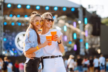Two young woman with beer at beach party. Summer holiday, vacation concept. Friendship and celebration concept.