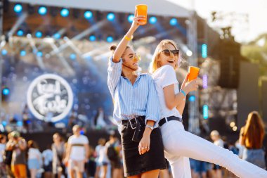 Plaj partisinde bira içen iki genç kadın. Yaz tatili, tatil konsepti. Arkadaşlık ve kutlama konsepti.