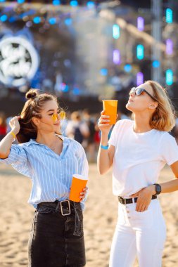 Two young woman with beer at beach party. Summer holiday, vacation concept. Friendship and celebration concept.