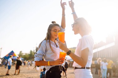 Plaj partisinde bira içen iki genç kadın. Yaz tatili, tatil konsepti. Arkadaşlık ve kutlama konsepti.
