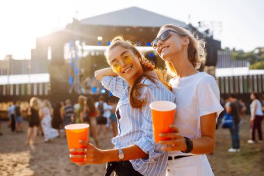 Two young woman with beer at beach party. Summer holiday, vacation concept. Friendship and celebration concept.