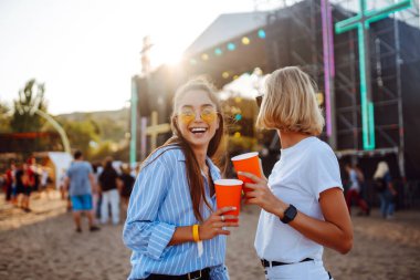 Two young woman with beer at beach party. Summer holiday, vacation concept. Friendship and celebration concept.