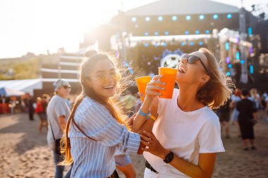 Two young woman with beer at beach party. Summer holiday, vacation concept. Friendship and celebration concept.