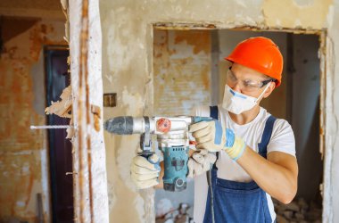 Repairer in boilersuit holding tools. Apartment repair and renovation concept. Building, working equipment and people concept.