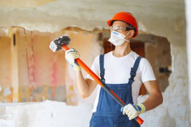 Klima giysisindeki tamirci aletleri tutuyor. Daire tamiri ve yenileme konsepti. İnşaat, çalışma ekipmanları ve insan konsepti.