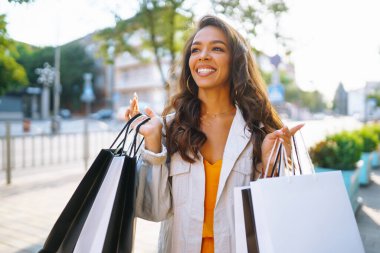 Alışveriş torbalarıyla sokakta yürüyen güzel bir kadın. Tüketim, satış, alım, alışveriş, yaşam tarzı konsepti.