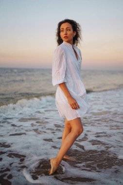 Beautiful woman walking along the seashore. People, freedom, lifestyle, travel and vacations concept.