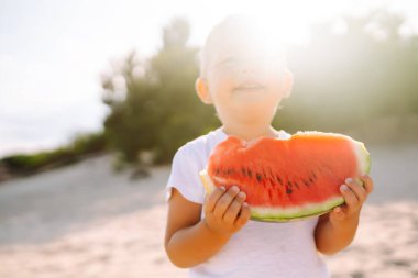 Funny kid eating watermelon outdoors.  Child, baby, healthy food. Youth lifestyle. Happiness, joy, holiday, beach, summer concept.