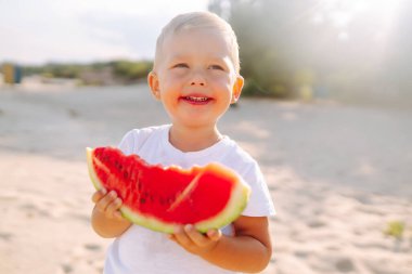 Funny kid eating watermelon outdoors.  Child, baby, healthy food. Youth lifestyle. Happiness, joy, holiday, beach, summer concept.