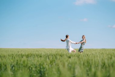 Two Beautiful posing  woman in the green field.  Fashion, style concept.