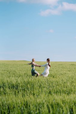 Two Beautiful posing  woman in the green field.  Fashion, style concept.