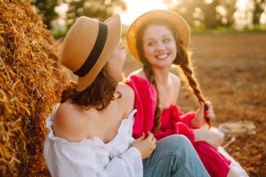 Two young woman near haystack at sunset. Fashion concept. Beautiful figures. Super mood. Summer concept.