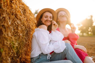 Two young woman near haystack at sunset. Fashion concept. Beautiful figures. Super mood. Summer concept.