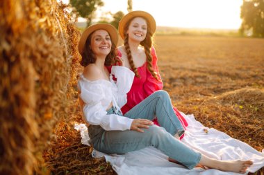 Two young woman near haystack at sunset. Fashion concept. Beautiful figures. Super mood. Summer concept.
