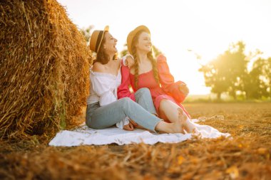 Two young woman near haystack at sunset. Fashion concept. Beautiful figures. Super mood. Summer concept.