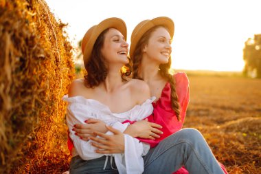 Two young woman near haystack at sunset. Fashion concept. Beautiful figures. Super mood. Summer concept.