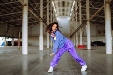 Funky young woman dancing alone in the street. Sport, dancing and urban culture concept. Fashion lifestyle.