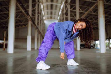 Funky young woman dancing alone in the street. Sport, dancing and urban culture concept. Fashion lifestyle.