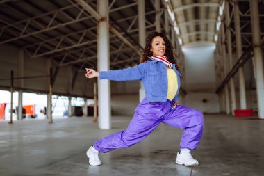 Funky young woman dancing alone in the street. Sport, dancing and urban culture concept. Fashion lifestyle.