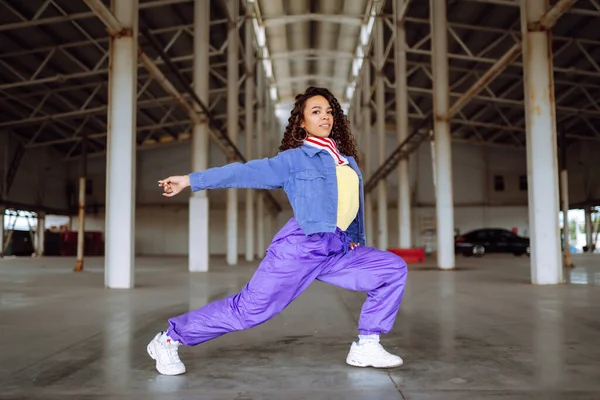 Funky young woman dancing alone in the street. Sport, dancing and urban culture concept. Fashion lifestyle.