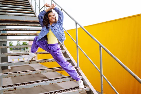 Funky young woman dancing alone in the street. Sport, dancing and urban culture concept. Fashion lifestyle.