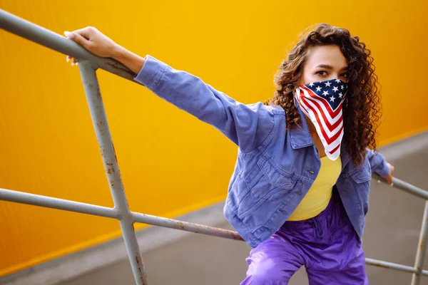 Funky young woman with american bandana dancing alone in the street. Sport, dancing and urban culture concept. US patriot.