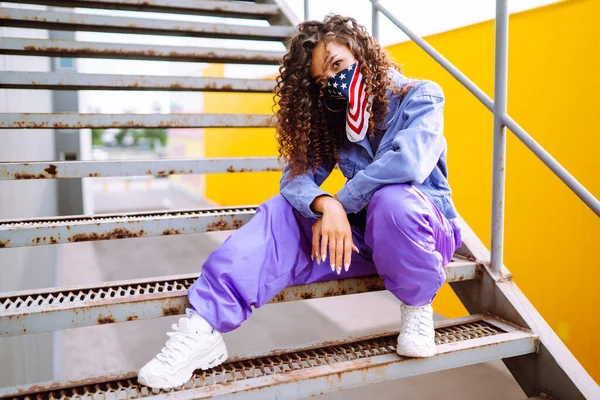 Funky young woman with american bandana dancing alone in the street. Sport, dancing and urban culture concept. US patriot.
