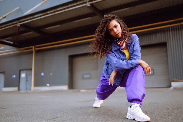 Funky young woman dancing alone in the street. Sport, dancing and urban culture concept. Fashion lifestyle.