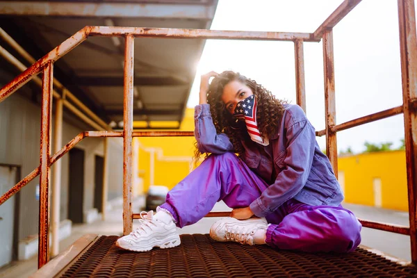 Funky young woman with american bandana dancing alone in the street. Sport, dancing and urban culture concept. US patriot.