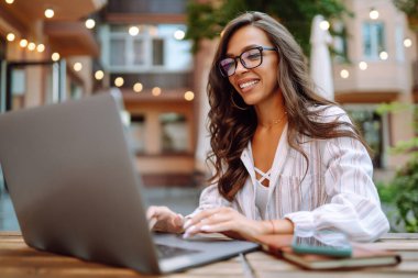 Smiling woman sitting in the cafe and working on laptop. Freelancer, business, online, education concept.