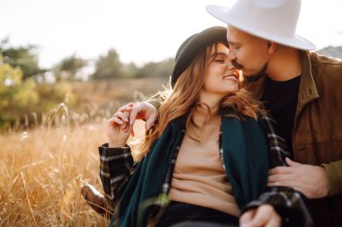 Lovely hipster couple resting in nature. People, lifestyle, relaxation and vacations concept. Autumn Fashion, style concept.