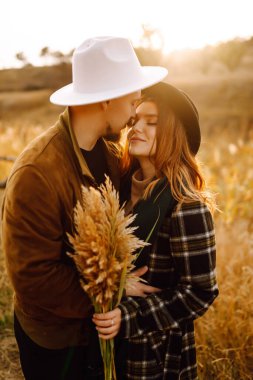 Lovely hipster couple resting in nature. People, lifestyle, relaxation and vacations concept. Autumn Fashion, style concept.