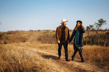 Lovely hipster couple resting in nature. People, lifestyle, relaxation and vacations concept. Autumn Fashion, style concept.