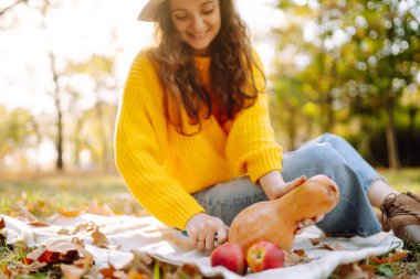 Fall picnic with pumpkin. Stylish woman enjoying autumn weather in the park. People, lifestyle, relaxation and vacations concept. Autumn harvest.